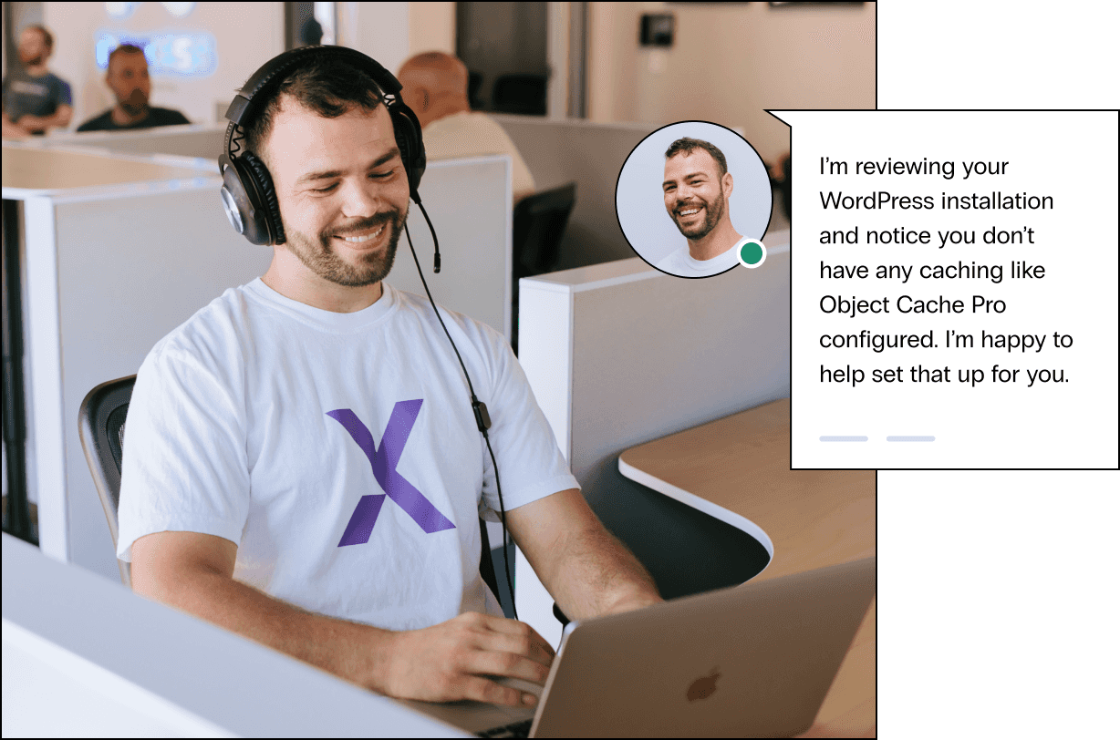 A tech support agent smiles at his desk as he begins a support chat, offering to set up website caching for the customer